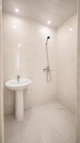 a white bathroom with a sink and a shower at Золотые пески in Bosteri