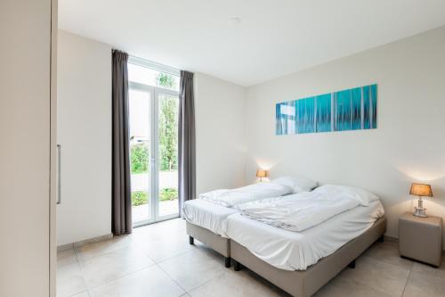 a white bedroom with a bed and a window at Group accommodation 123 in Valkenburg