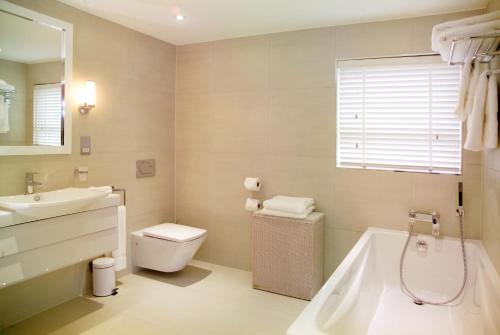 a bathroom with a toilet, bathtub, sink and tub at Hotel La Place in Saint Aubin