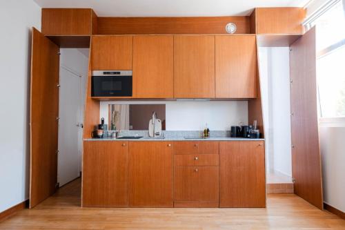 a kitchen with wooden cabinets and a sink at Studio Design Paris 20 min RER A in Nogent-sur-Marne