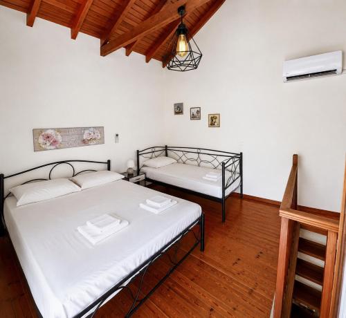 a bedroom with two beds and a wooden floor at Pozzo House Corfu - Traditional House for 3 near Agios Georgios Beach in Argyrádes