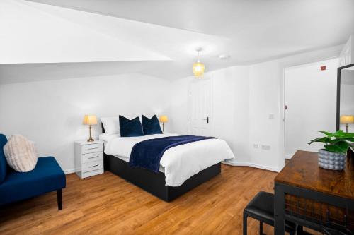 a white bedroom with a bed and a blue chair at Providence Suites 1 Bedroom Sleeps 4 Perfect for Contractors and Families and Solo Travellers in Fallings Park