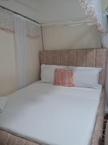 a white bed with a red pillow on it at PAZURI - Homes in Voi