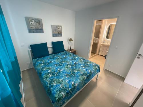 a bedroom with a bed with a blue blanket at Blue sunset - Appartement avec vue mer in Papeete