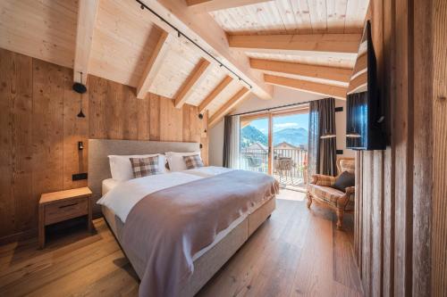 a bedroom with a large bed and a large window at AlpeLuce Mountain Chalet in Arabba