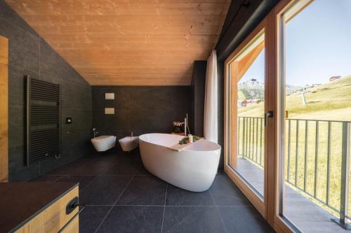 a bathroom with two white tubs and a window at AlpeLuce Mountain Chalet in Arabba