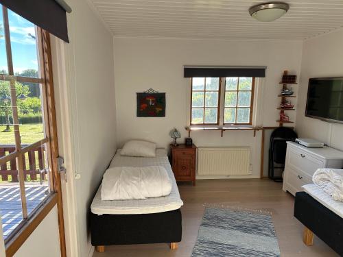 a bedroom with two beds and a tv and a balcony at Charmiga Norrangen in Väddö