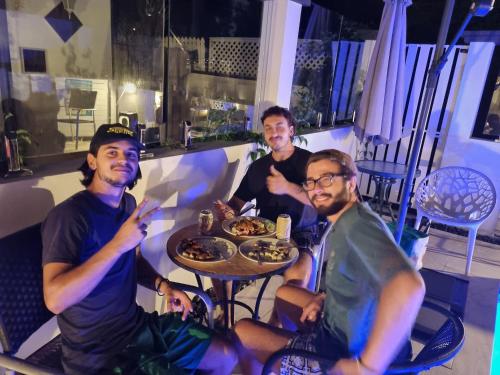 three men sitting at a table eating food at Backpackers Homestay 21-36 yrs ONLY in Caloundra