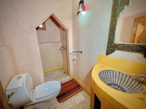 a bathroom with a toilet and a sink with a mirror at Riad Belgika Marrakech in Ourika