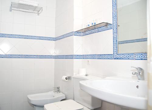 Un baño con lavabo, inodoro y espejo. en Hotel Reino Nevado, en Sierra Nevada