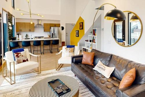 a living room with a leather couch and a kitchen at Illume 407 in Nashville