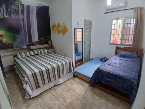 a bedroom with two beds and a mirror at Casa aconchegante in Manaus