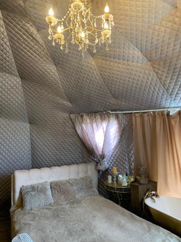 a bedroom with a ceiling with a bed and a chandelier at Couple Baltic Coast Retreat in Apšuciems