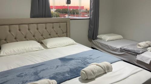 two twin beds in a room with a window at Harmony House Hospedagem in Votuporanga