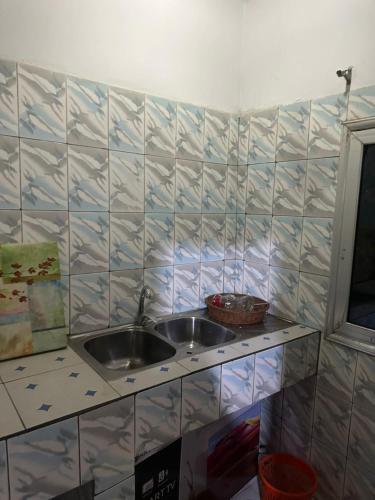 a kitchen with two sinks and a tiled wall at Cosy appartement à Nongo in Conakry