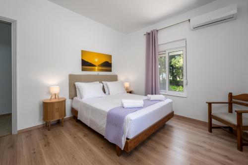 a bedroom with a large white bed and a window at Polytimi Summerhouse in Ialysos