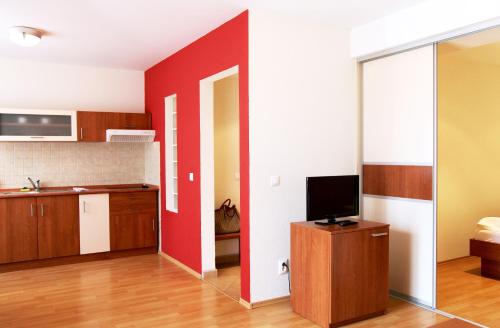 a kitchen with a red wall and a television at Urpí­n City Residence in Banská Bystrica