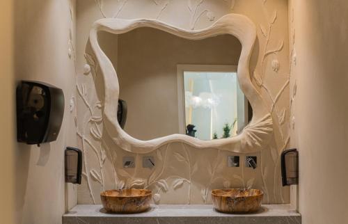 ein Spiegel im Badezimmer mit zwei Holzschalen in der Unterkunft Avaris Hotel in Dhërmi