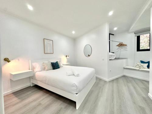 a white bedroom with a white bed and a mirror at Waves Madeira II in Caniçal