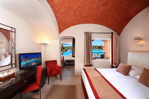 um quarto com uma cama e uma televisão num quarto em Jaz Makadi Oasis Resort em Hurghada