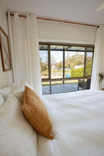 a white bed with a pillow in front of a window at The Mullet in Nambucca Heads
