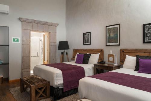 a hotel room with two beds with purple sheets at Casa Brunella - Hotel Boutique Querétaro in Querétaro