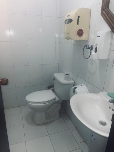 a white bathroom with a toilet and a sink at Hotel Charmin in Gaira