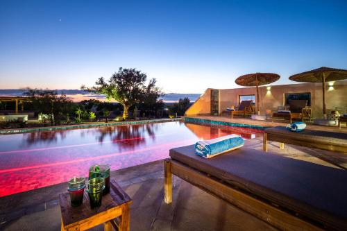 a swimming pool with benches and umbrellas next to it at Villa de luxe Sakina in Essaouira