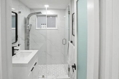 a white bathroom with a shower and a sink at Mango Tree House in Hialeah