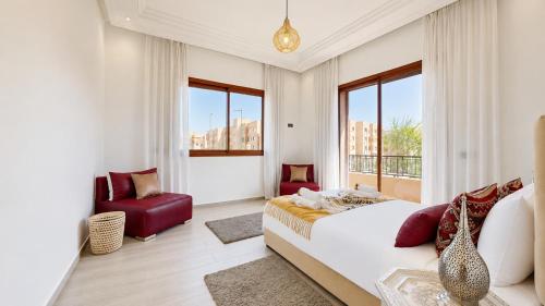 a bedroom with a bed and a chair and windows at Villa Amroth in Marrakesh