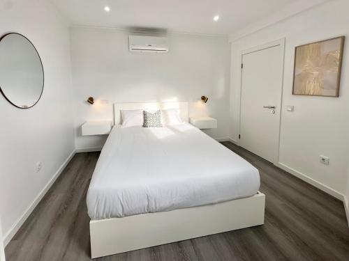 a white bedroom with a white bed and a mirror at Waves Madeira I in Caniçal