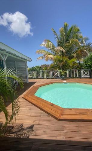 a swimming pool on a wooden deck next to a house at Papaye et coconut in Anse-Bertrand