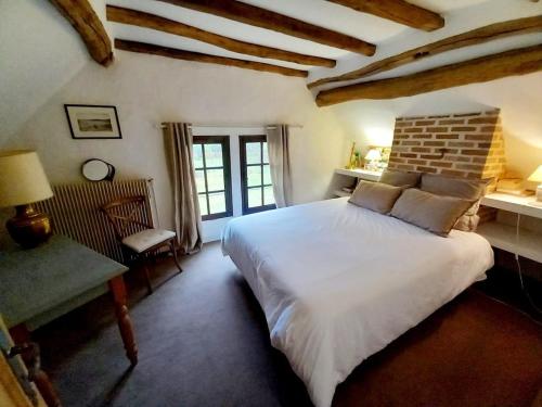 a bedroom with a large white bed and a chair at Les Gordons in Chaumont-sur-Tharonne