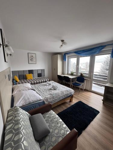a bedroom with two beds and a living room with a table at Na Snozie in Milówka