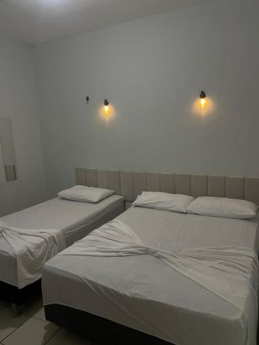 two beds in a room with lights on the wall at Pousada Casa Bali in Fortaleza