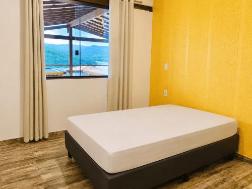 a bed in a room with a large window at Casa com Vista inigualável "Vista del Lago" in Capitólio