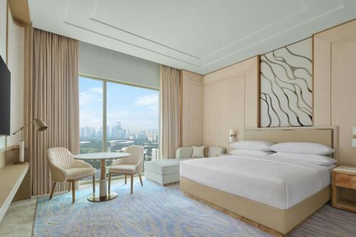 a bedroom with a bed and a table and chairs at Jakarta Marriott Hotel Gelora in Jakarta
