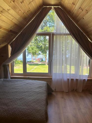 a bedroom with a bed and a large window at Dadajówka Domki przy plaży in Wilimy