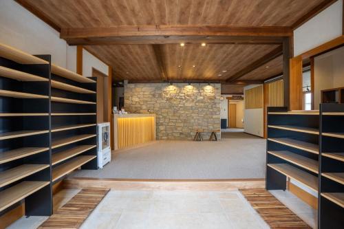 a large room with wooden ceilings and a stone wall at メイプルハイム in Iiyama