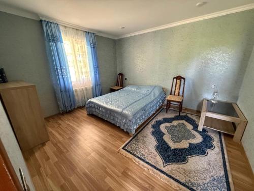 a bedroom with a bed and a chair and a rug at Relax in mountains in İsmayıllı