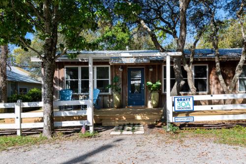 ein kleines Haus mit Zaun und blauer Tür in der Unterkunft Artless Sprite in Santa Rosa Beach