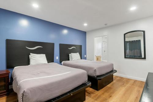 a bedroom with two beds and a mirror at Encore Inn Inglewood in Inglewood