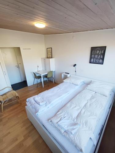 a large white bed in a room with a table at Double room 5 with Free Parking in Nørresundby