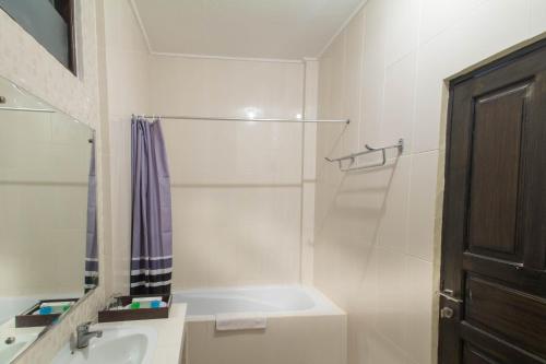 a white bathroom with a sink and a shower at Bali Sandy Resort in Kuta