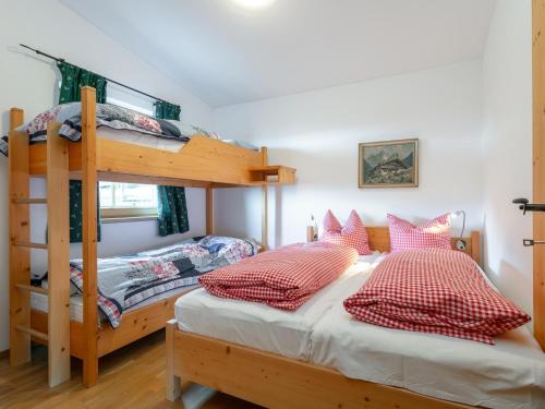 ein Schlafzimmer mit zwei Etagenbetten und rot-weißen Kissen in der Unterkunft Schneeberghütte in Thiersee