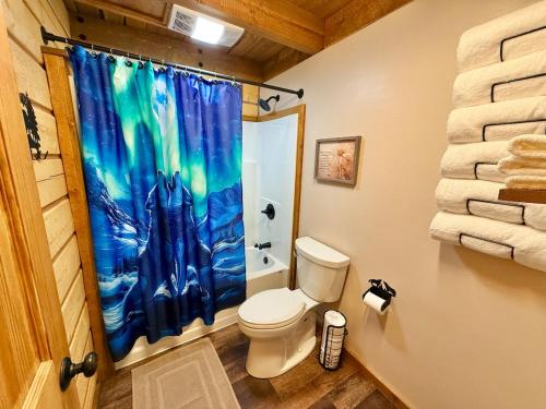 a bathroom with a toilet and a shower curtain at Riverfront, Authentic, Luxury Log Cabin-Gray Wolf in Wasilla