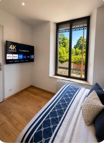 a bedroom with a bed and a tv on the wall at La Maison du faubourg & Spa in Vitry-le-François