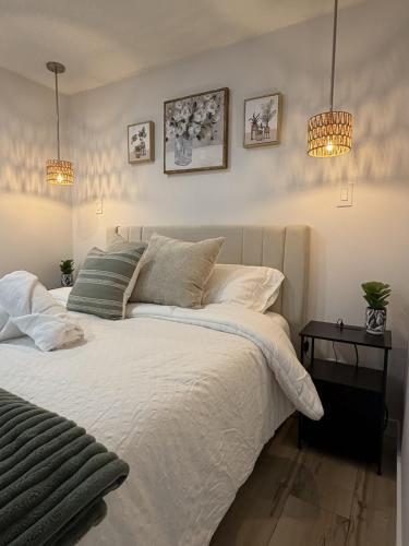 a bedroom with a white bed and two lights at The Ogieva Suites in Airdrie