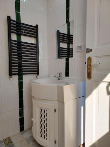 a white bathroom with a sink and a mirror at House Near the Sky in Dar Salah Bey