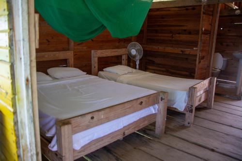 two twin beds in a room with wooden walls at Cabañas Wailidub, San Blas in Ogobsitupo